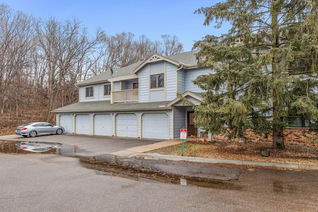 view of property featuring a garage, driveway, and a shingled roof