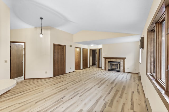 unfurnished living room featuring lofted ceiling, a brick fireplace, light wood-style flooring, and baseboards