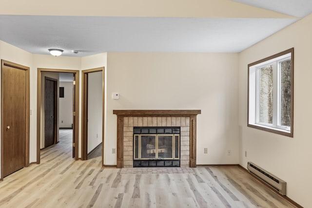 unfurnished living room with light wood-type flooring, a fireplace, baseboards, and baseboard heating