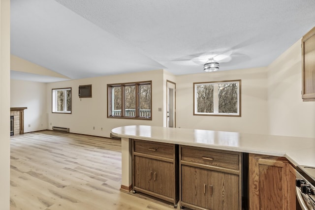 kitchen with light wood finished floors, light countertops, a baseboard heating unit, stainless steel range oven, and a peninsula