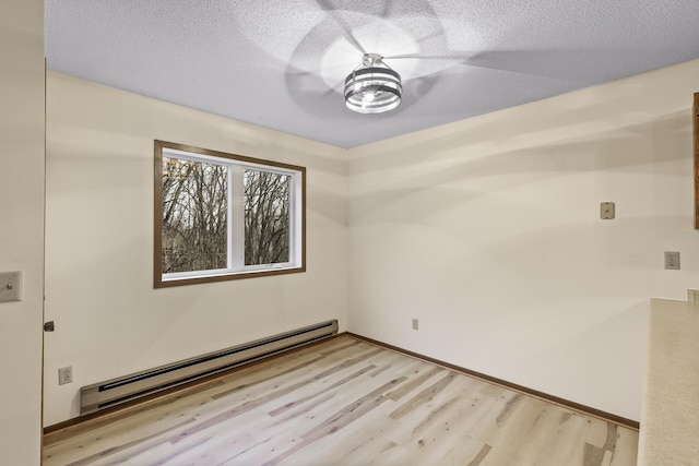 empty room featuring a baseboard heating unit, a textured ceiling, light wood-type flooring, and baseboards