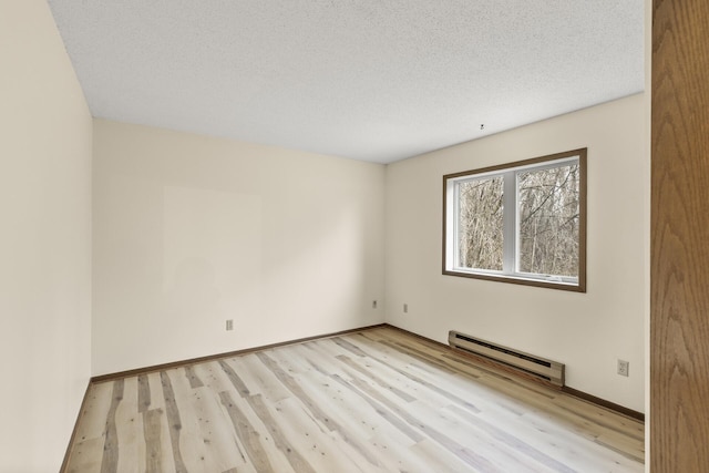 empty room featuring a textured ceiling, baseboards, baseboard heating, and wood finished floors