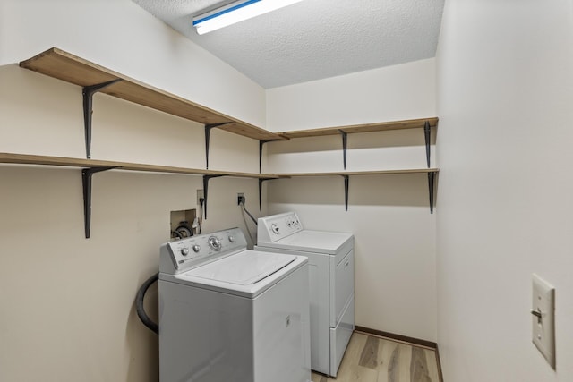 laundry area featuring light wood-type flooring, laundry area, separate washer and dryer, and a textured ceiling