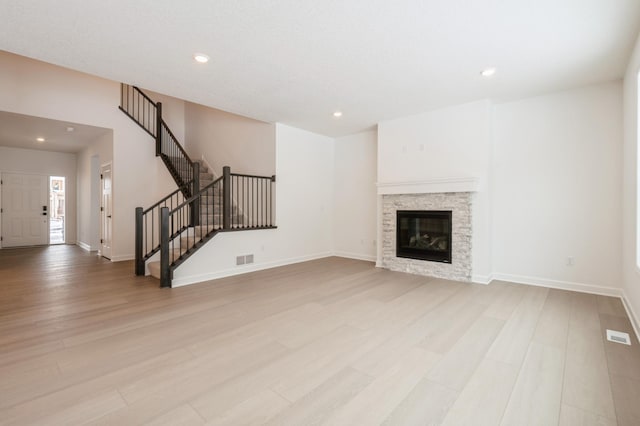 unfurnished living room featuring light wood finished floors, stairs, visible vents, and recessed lighting