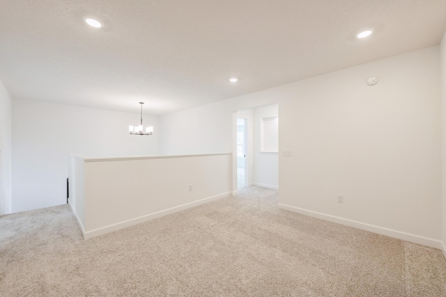 unfurnished room with recessed lighting, light colored carpet, a notable chandelier, and baseboards