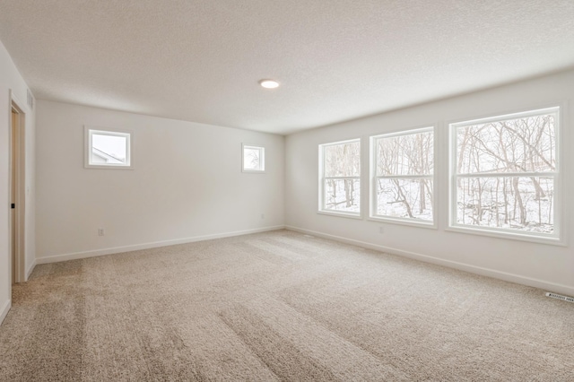 unfurnished room featuring a healthy amount of sunlight, light colored carpet, visible vents, and baseboards