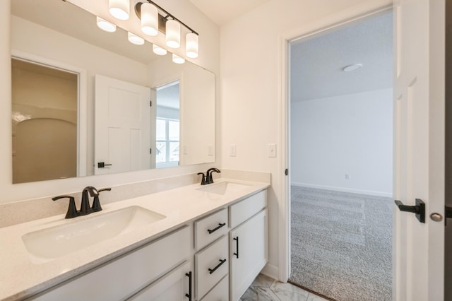 bathroom featuring double vanity, baseboards, and a sink