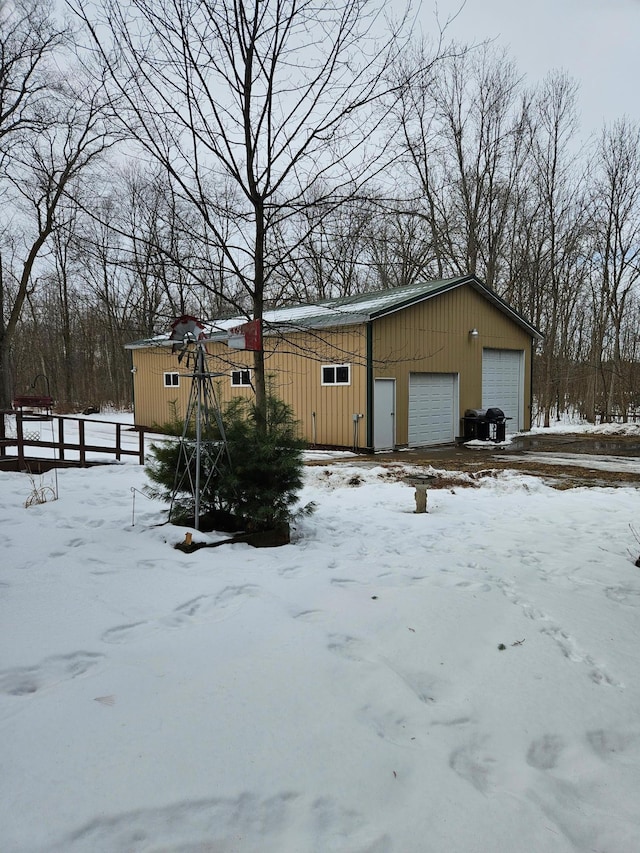 snow covered garage with a garage and fence