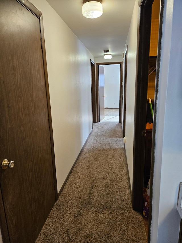 corridor featuring baseboards and carpet flooring