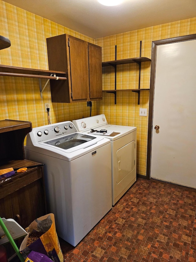 washroom with washer and dryer, cabinet space, and wallpapered walls