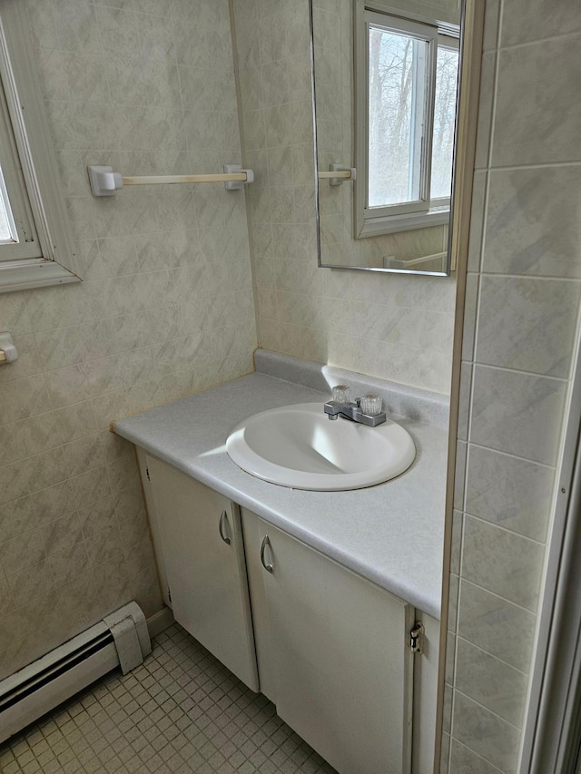 bathroom with a baseboard radiator, tile walls, vanity, and tile patterned flooring