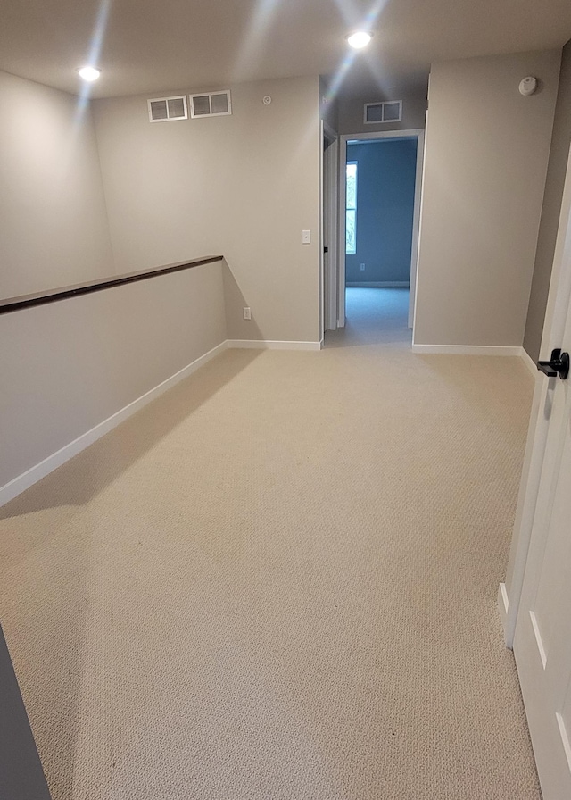 unfurnished room with light carpet, visible vents, and baseboards