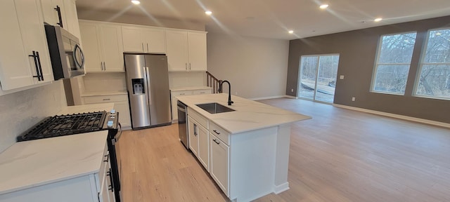 kitchen with light wood-style flooring, white cabinetry, stainless steel appliances, and a sink