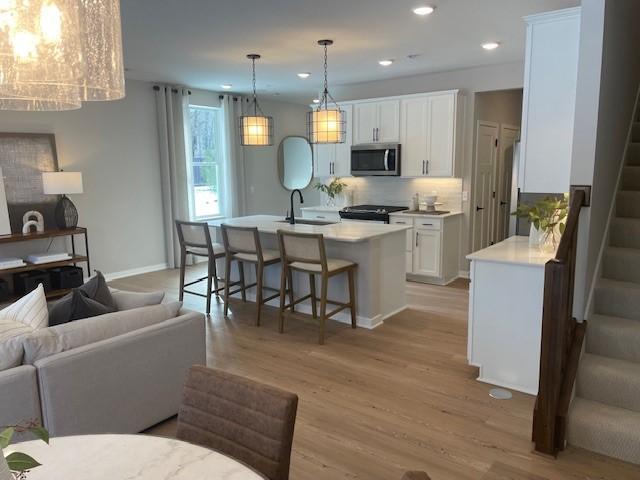 kitchen featuring light wood-style flooring, stainless steel microwave, open floor plan, and light countertops