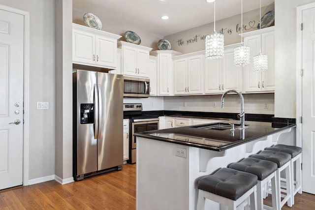 kitchen featuring white cabinetry, a peninsula, appliances with stainless steel finishes, and a sink