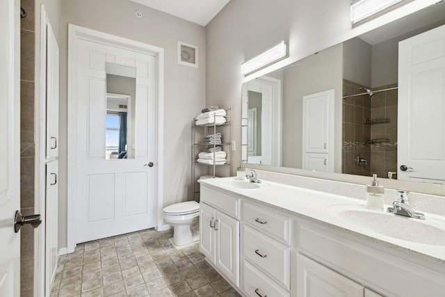 full bath featuring a sink, tiled shower, toilet, and double vanity