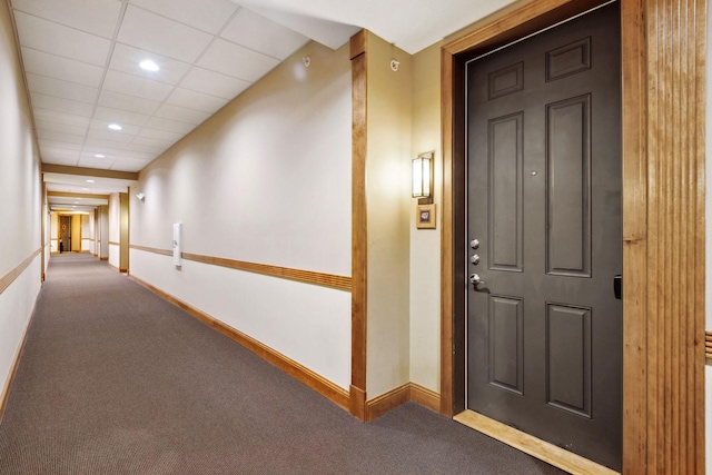 hallway with recessed lighting, a drop ceiling, carpet floors, and baseboards