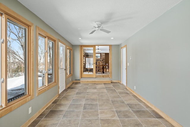 unfurnished sunroom featuring ceiling fan