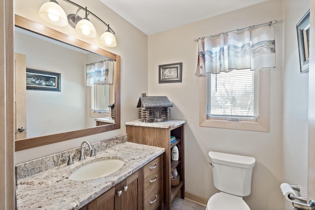 bathroom featuring toilet, vanity, and baseboards