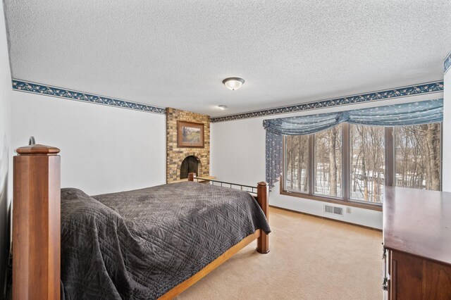 carpeted bedroom featuring visible vents, a textured ceiling, and a large fireplace