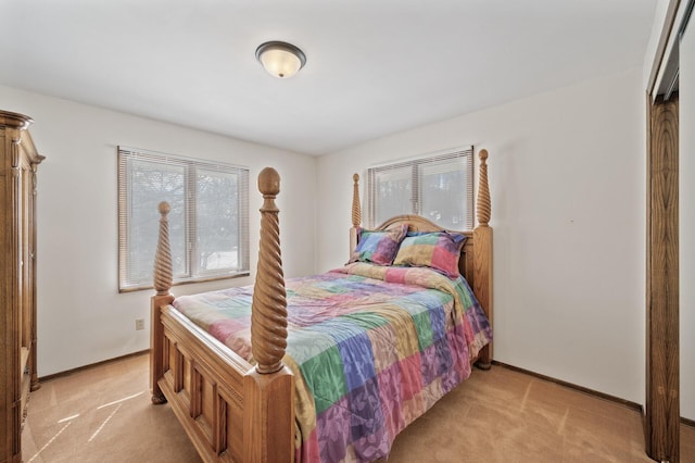 bedroom with multiple windows, light carpet, and baseboards