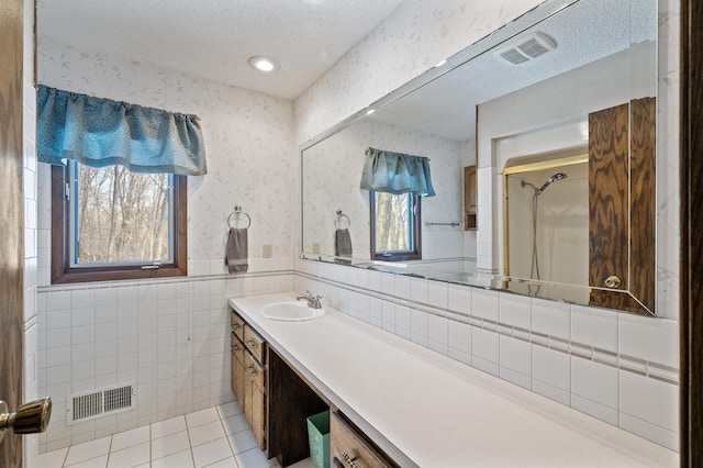 bathroom with tile patterned floors, visible vents, a textured ceiling, and wallpapered walls