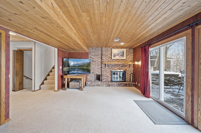 carpeted living room featuring stairway, a brick fireplace, and wood ceiling