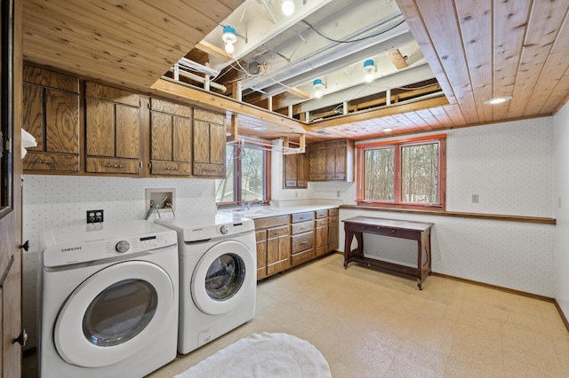 laundry room featuring cabinet space, wallpapered walls, baseboards, light floors, and washing machine and clothes dryer