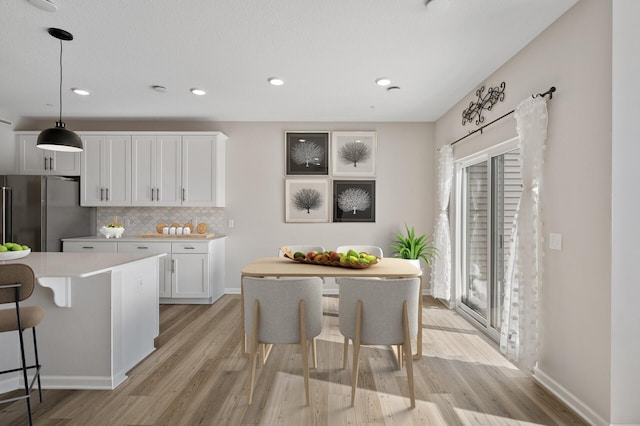 kitchen featuring a kitchen bar, light countertops, white cabinets, and freestanding refrigerator