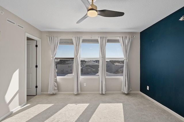 spare room with carpet flooring, a ceiling fan, baseboards, and a textured ceiling