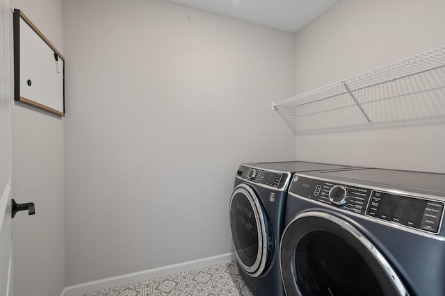 clothes washing area with laundry area, washing machine and dryer, and baseboards