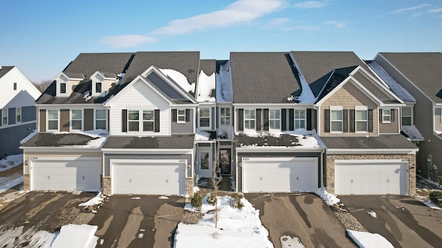 view of property with a garage, stone siding, a residential view, and aphalt driveway