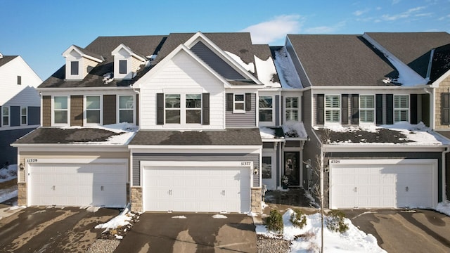 view of property with aphalt driveway, stone siding, and a garage