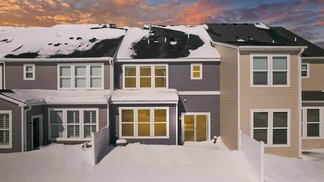 snow covered rear of property with fence