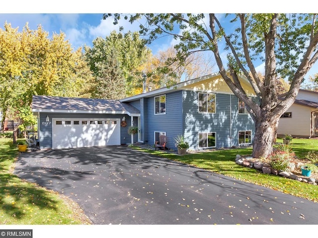 split level home with a garage, driveway, and a front lawn