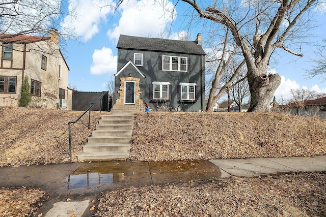 view of front of house with a chimney and fence