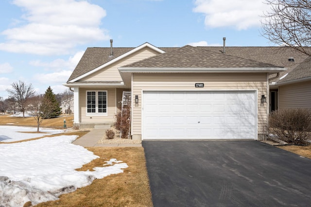 view of front facade featuring driveway, an attached garage, and roof with shingles