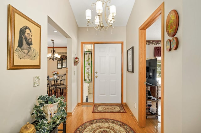 foyer featuring baseboards, light wood finished floors, and a chandelier