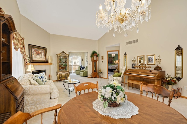 carpeted dining space with visible vents, high vaulted ceiling, a notable chandelier, a tiled fireplace, and baseboards