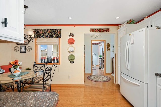 kitchen featuring white cabinetry, freestanding refrigerator, light wood-style floors, crown molding, and baseboards