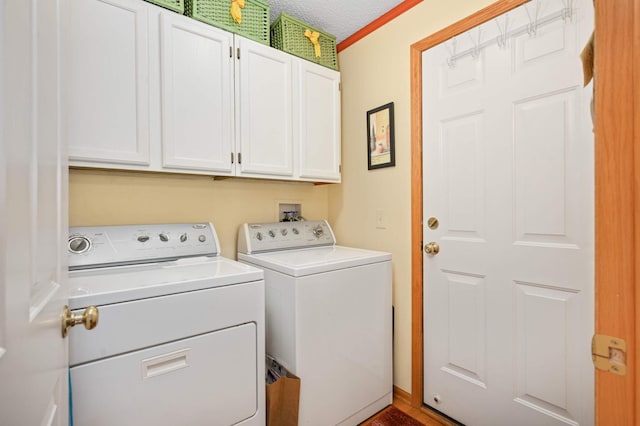 laundry area featuring washer and clothes dryer, cabinet space, and a textured ceiling