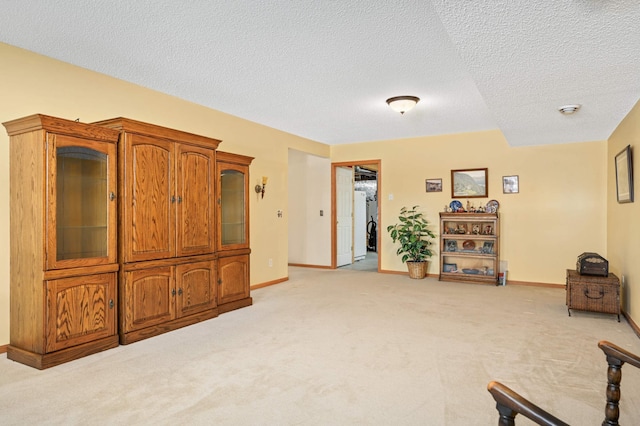 living area featuring light carpet, a textured ceiling, and baseboards