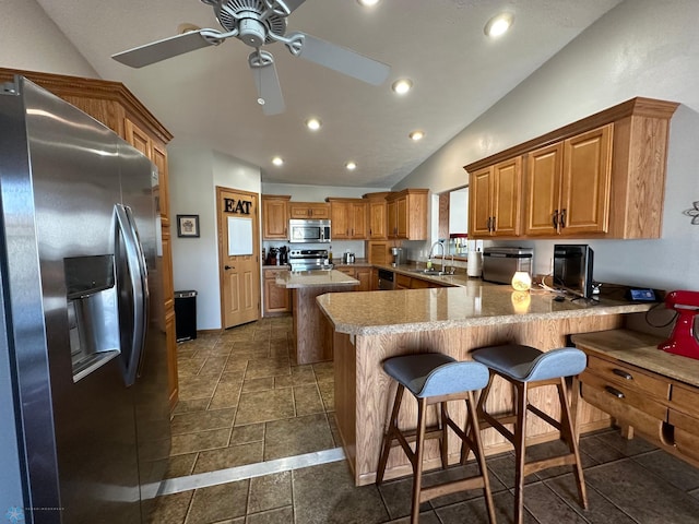 kitchen featuring a peninsula, a breakfast bar area, stainless steel appliances, and a sink