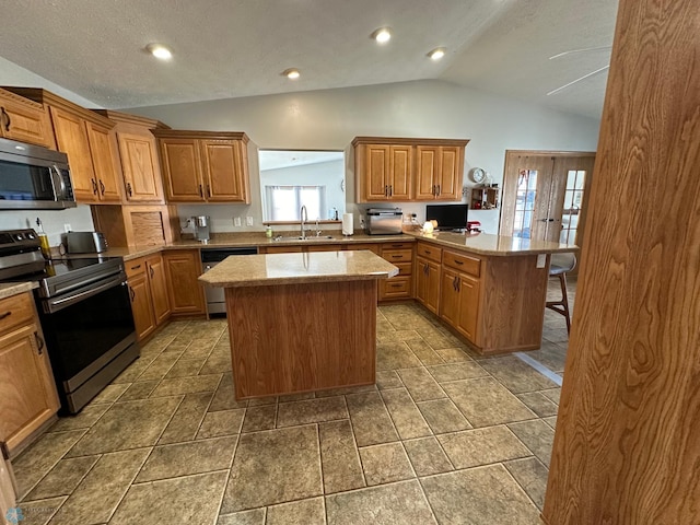 kitchen featuring lofted ceiling, a kitchen island, a peninsula, stainless steel appliances, and a sink