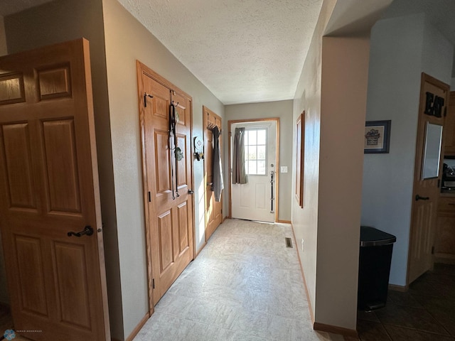 entryway with a textured ceiling and baseboards