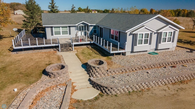 view of front facade featuring a deck, an outdoor fire pit, and a shingled roof