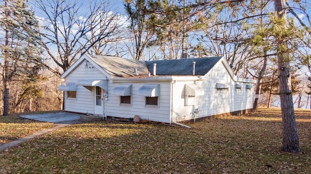 view of front of home with a front lawn and a shingled roof