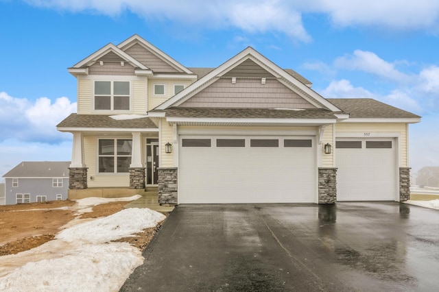 craftsman-style home featuring stone siding, aphalt driveway, and an attached garage