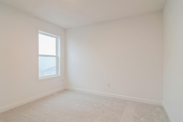 spare room with baseboards, visible vents, and light colored carpet