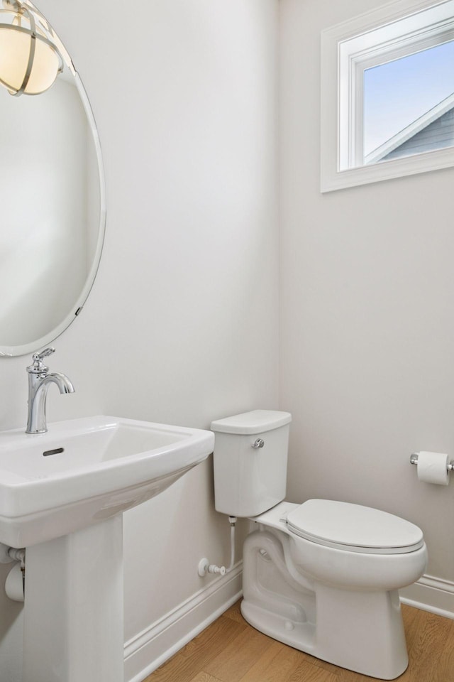 bathroom featuring a sink, baseboards, toilet, and wood finished floors